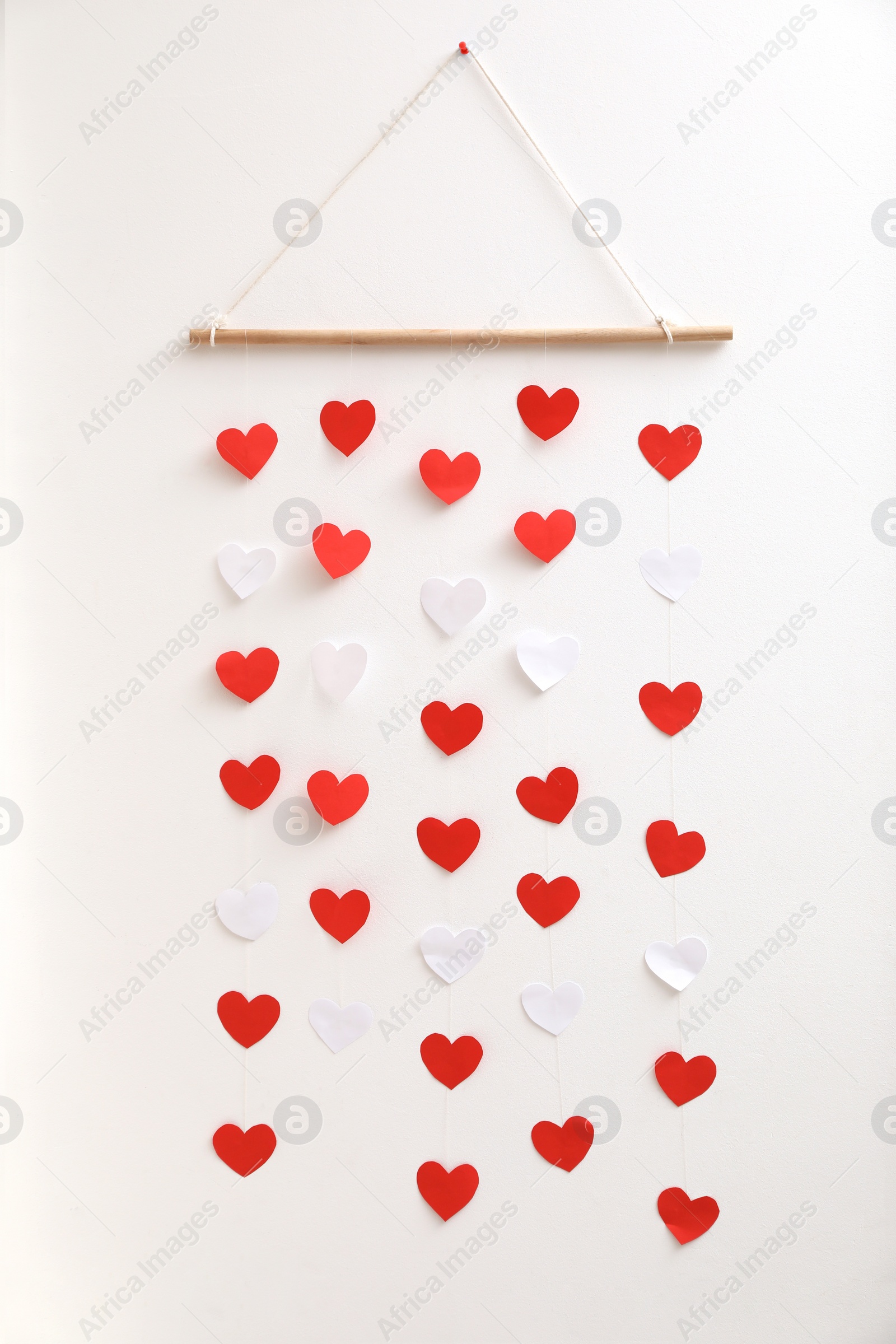 Photo of Beautiful decor element with hearts on white wall. Valentine's Day celebration