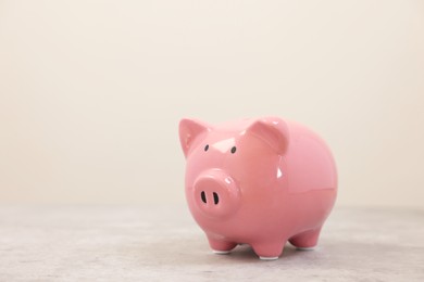 Pink piggy bank on grey table, space for text