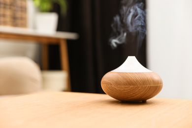 Photo of Aroma oil diffuser on wooden table at home, space for text. Air freshener