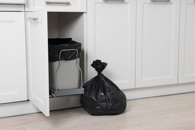 Photo of Plastic garbage bag and trash can indoors. Space for text