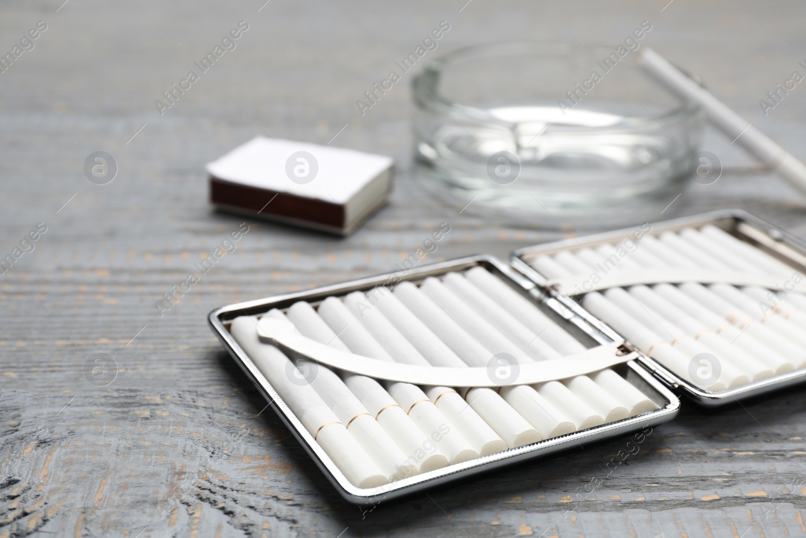 Photo of Stylish case with cigarettes on grey wooden table, closeup. Space for text