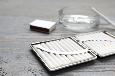 Stylish case with cigarettes on grey wooden table, closeup. Space for text