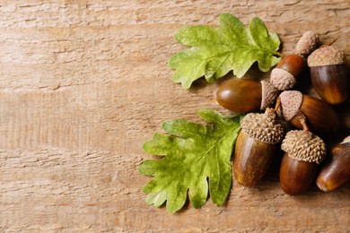 Photo of Pile of acorns and oak leaves on wooden table. Space for text