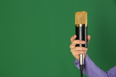Photo of Child holding microphone on color background, closeup. Space for text