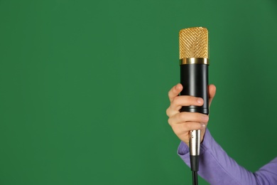 Child holding microphone on color background, closeup. Space for text