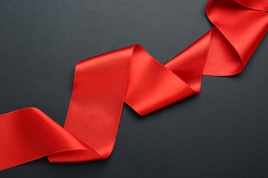 Photo of Beautiful red ribbon on black background, top view