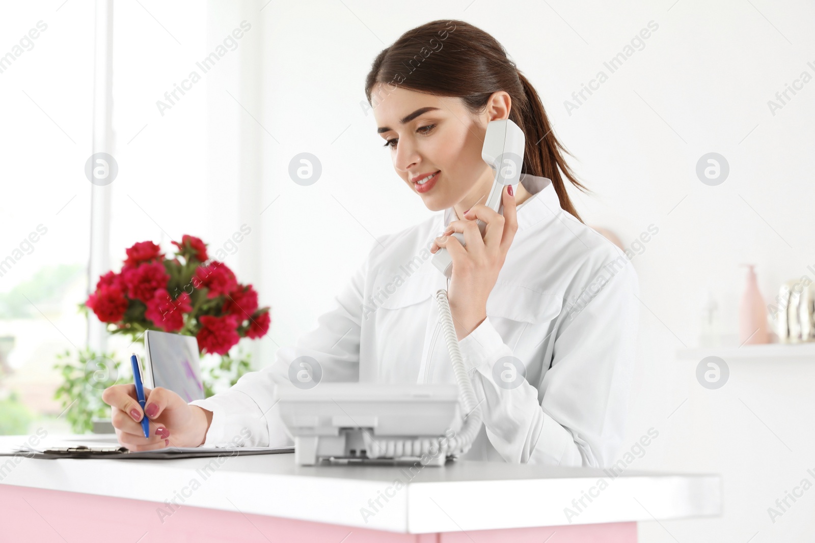 Photo of Beauty salon receptionist talking on phone at desk