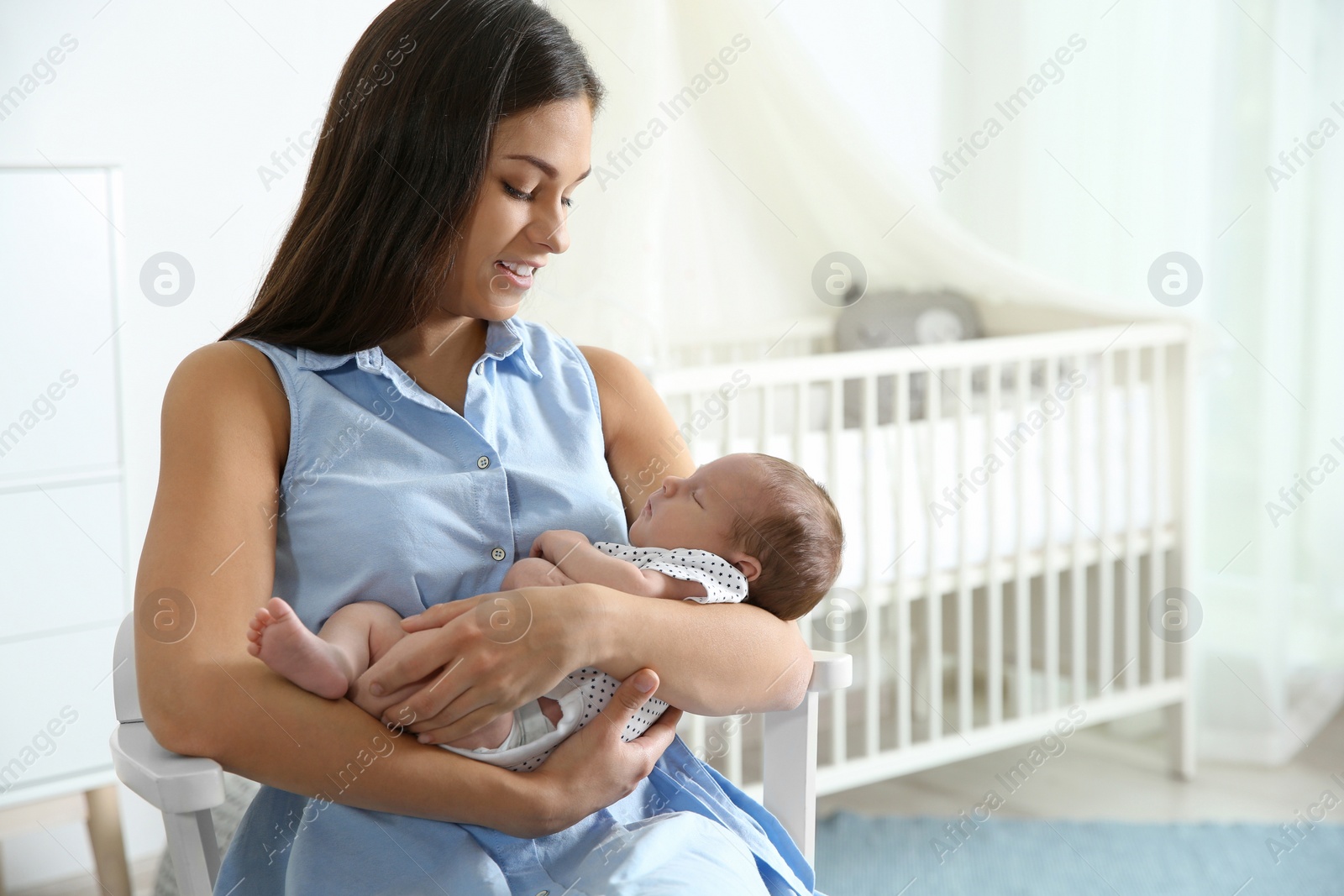 Photo of Young woman with her newborn baby at home. Space for text