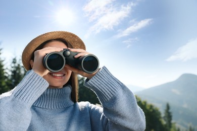 Photo of Young woman with binoculars in mountains on sunny day