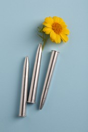 Photo of Bullets and beautiful flower on light blue background, flat lay