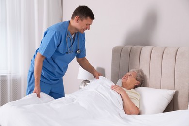 Photo of Caregiver assisting senior woman in bedroom. Home health care service