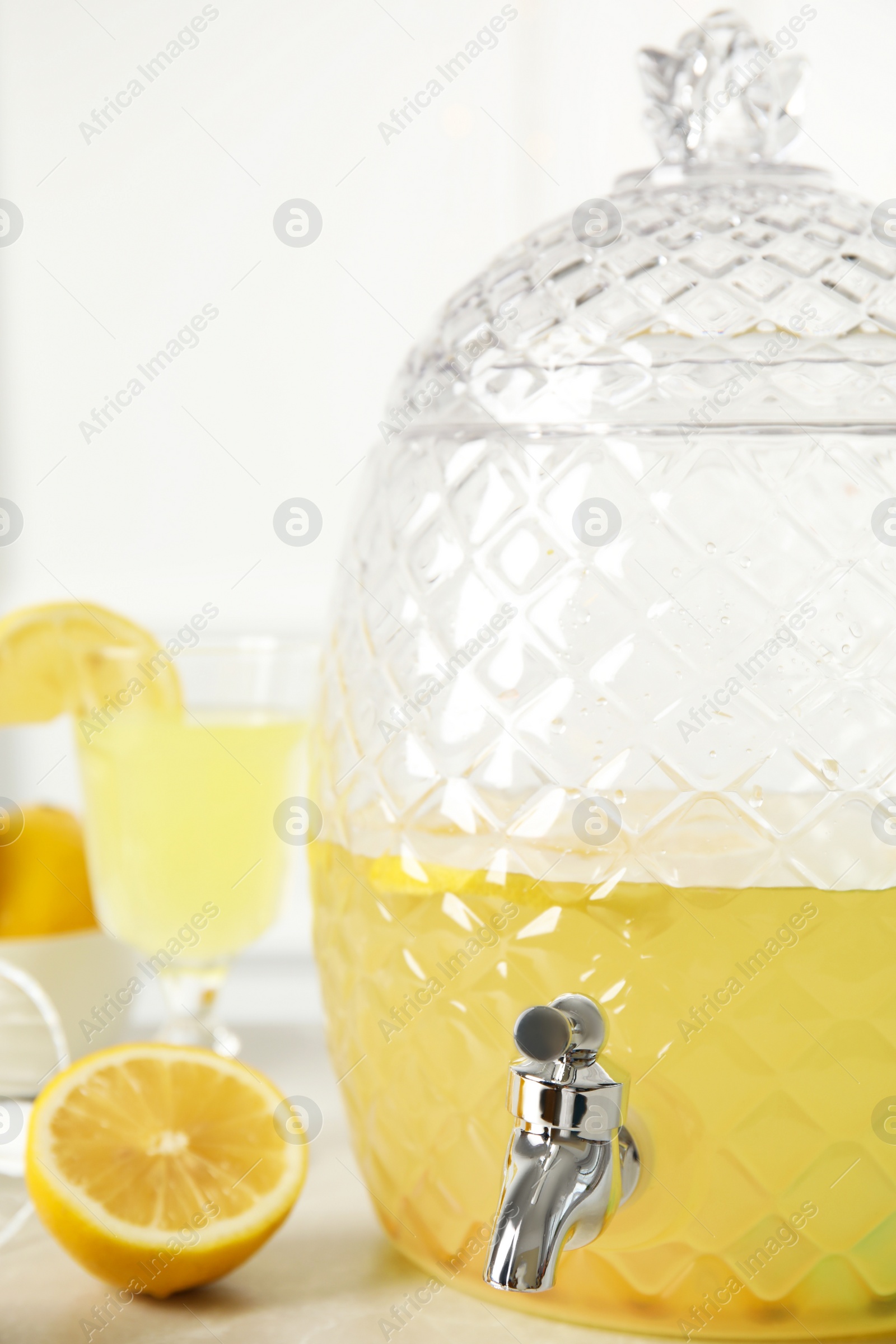 Photo of Beverage dispenser with delicious lemonade on light table