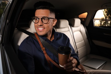 Businessman with cup of drink in modern taxi