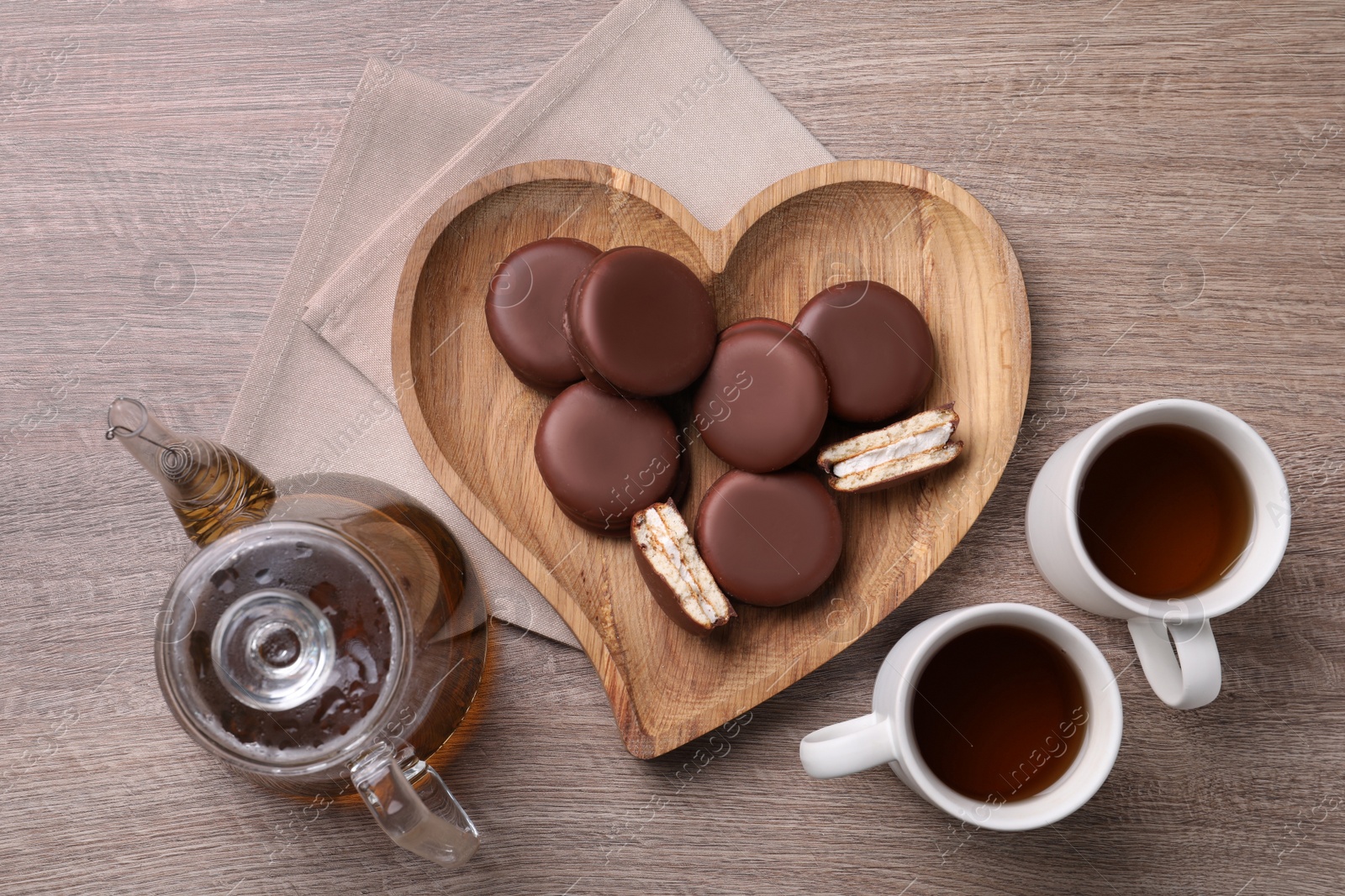 Photo of Tasty choco pies and tea on wooden table, flat lay