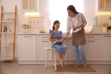 Mother and daughter wiping dishes together in kitchen