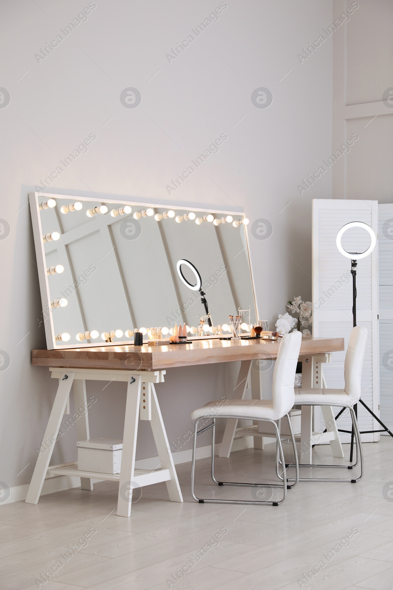 Photo of Modern mirror with light bulbs on dressing table in makeup room