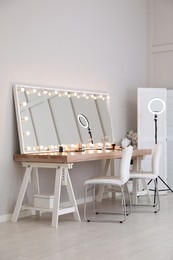 Photo of Modern mirror with light bulbs on dressing table in makeup room