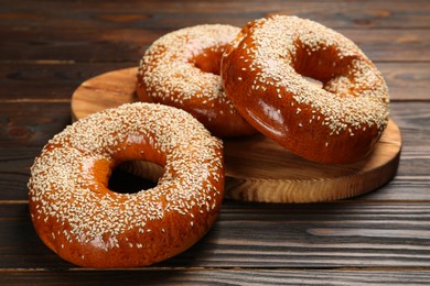 Delicious fresh bagels with sesame seeds on wooden table