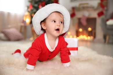 Cute little baby in Christmas costume crawling on fur rug at home