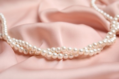 Photo of Beautiful white pearls on delicate pink silk