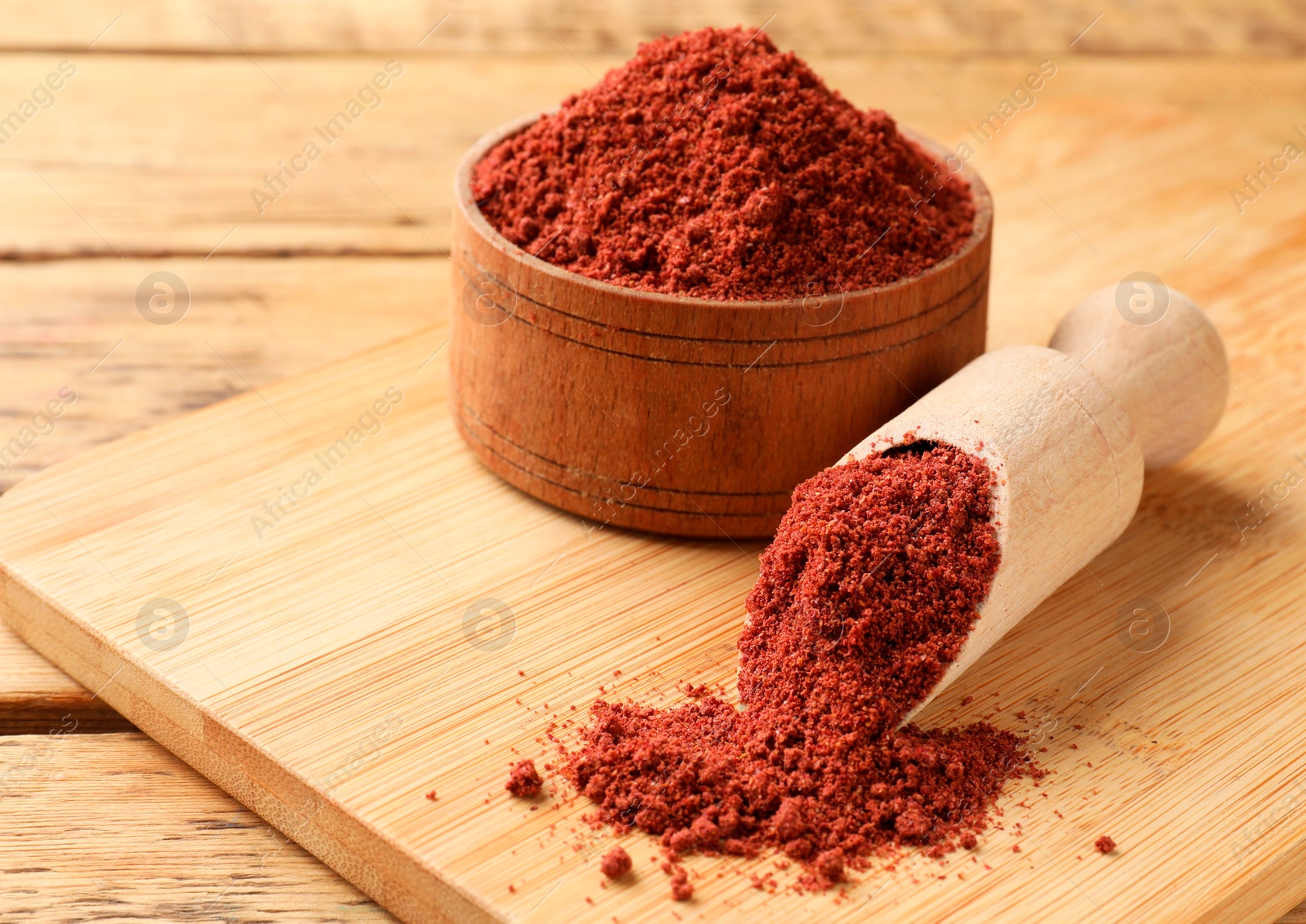 Photo of Scoop and bowl with cranberry powder on wooden table, closeup. Space for text