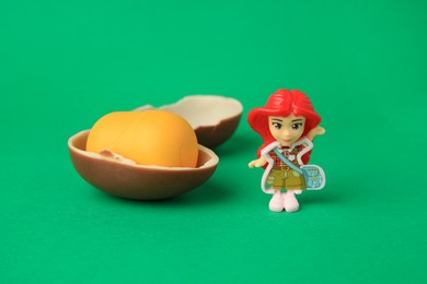 Photo of Slynchev Bryag, Bulgaria - May 25, 2023: Halves of Kinder Surprise Egg, plastic capsule and toy on green background