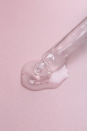 Photo of Pipette with cosmetic serum on pink background