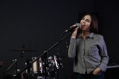 Photo of Young singer with microphone recording song in studio. Space for text