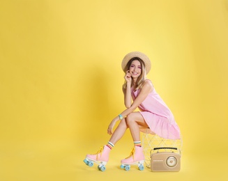 Photo of Young woman with roller skates and retro radio on color background, space for text