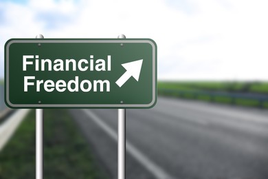 Image of Road sign with words Financial Freedom and arrow outdoors, space for text