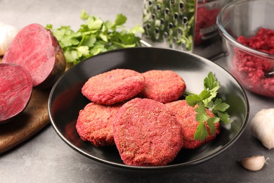Photo of Delicious beetroot cutlets and parsley in black bowl on light gray table. Vegan dish