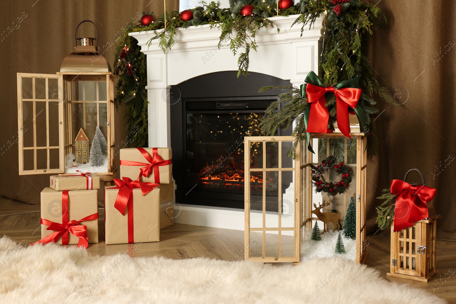 Photo of Beautiful Christmas lanterns and presents near fireplace in room with festive decor