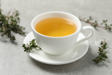 Photo of Aromatic herbal tea with thyme on light grey table, closeup