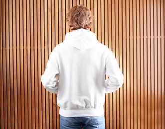 Photo of Man in hoodie sweater on wooden background. Space for design