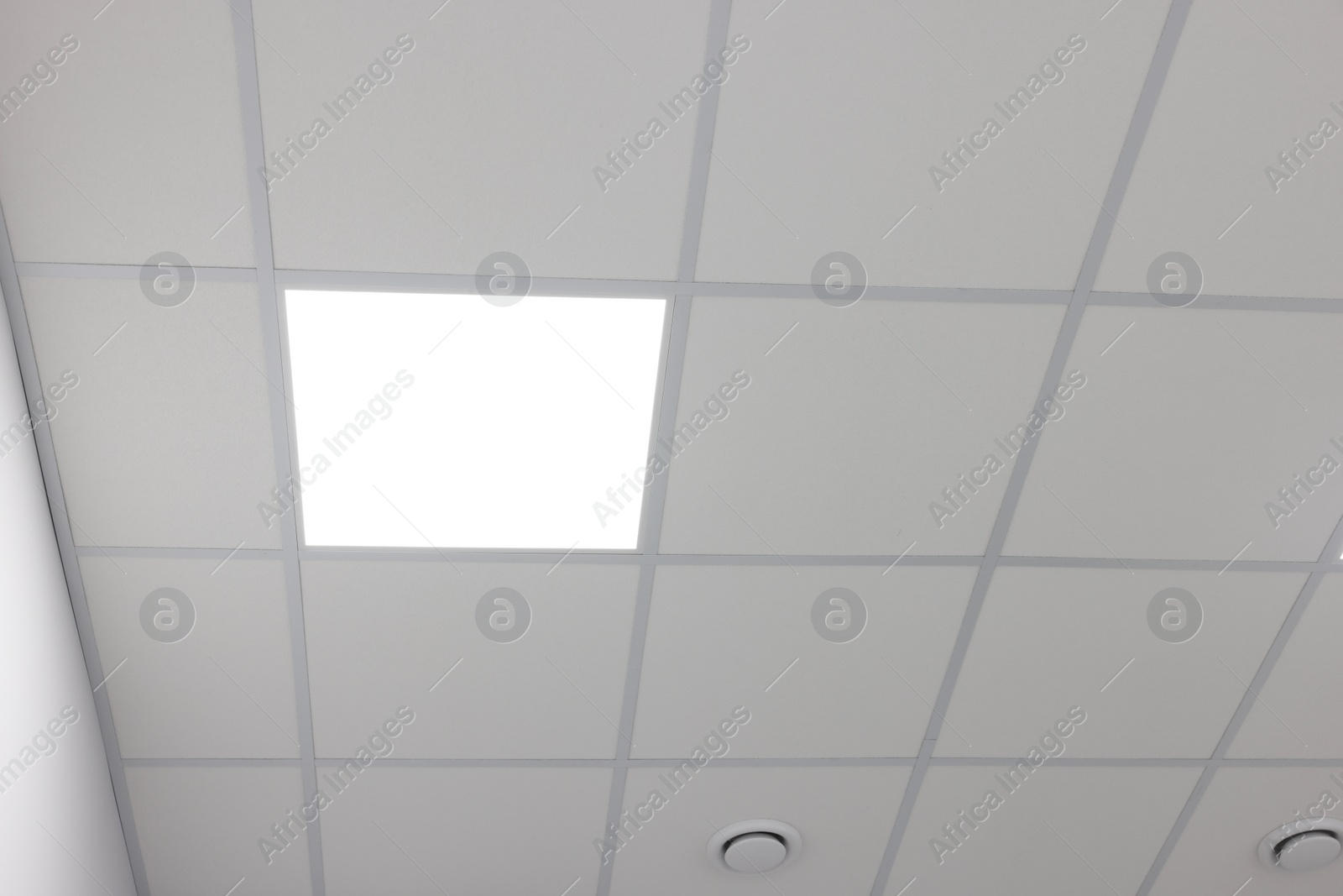 Photo of White ceiling with PVC tiles and lighting indoors, low angle view