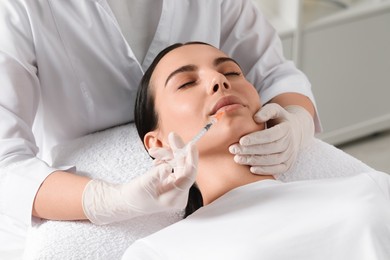 Doctor giving lips injection to young woman in clinic. Cosmetic surgery