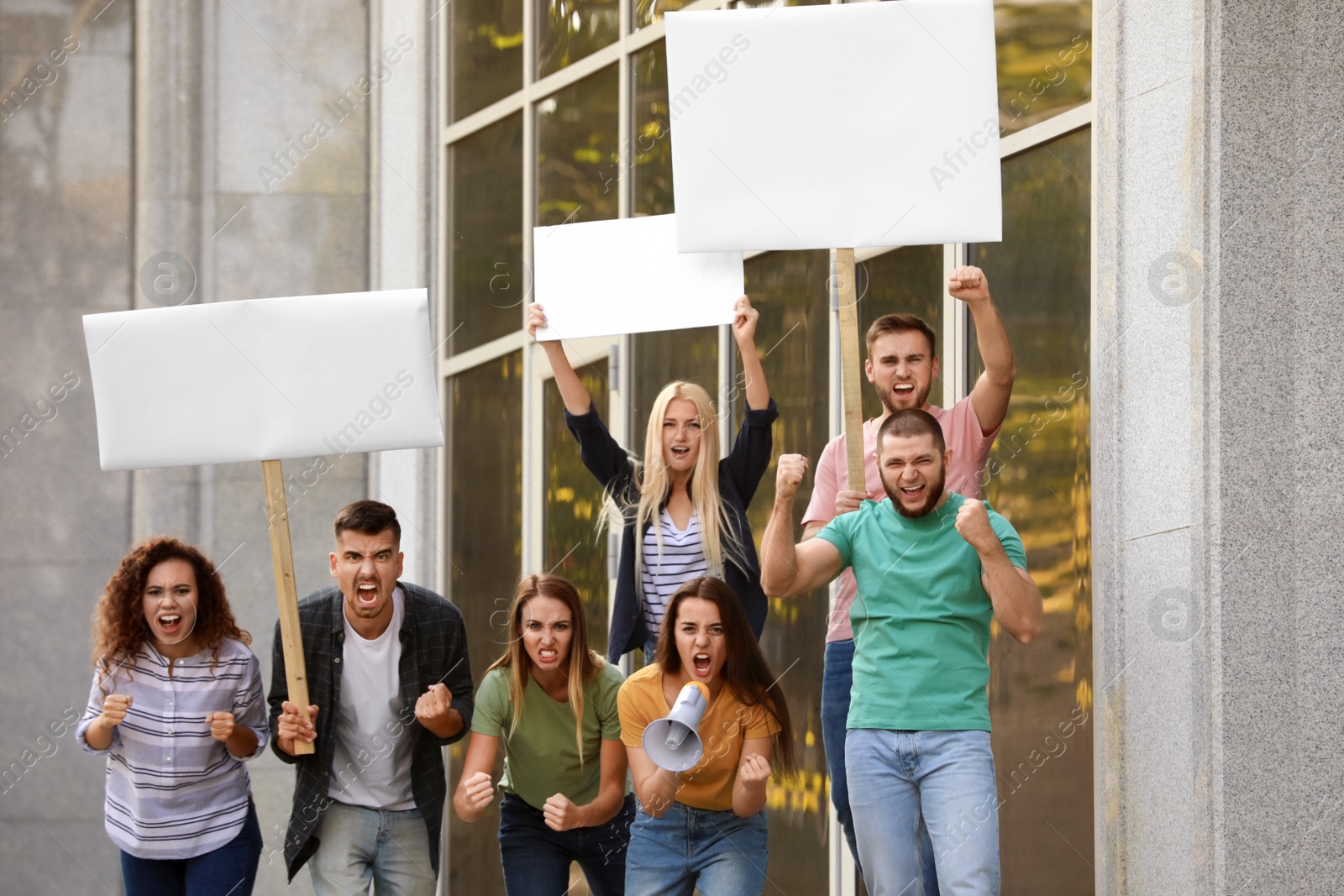 Photo of Angry young woman with megaphone leading protest outdoors