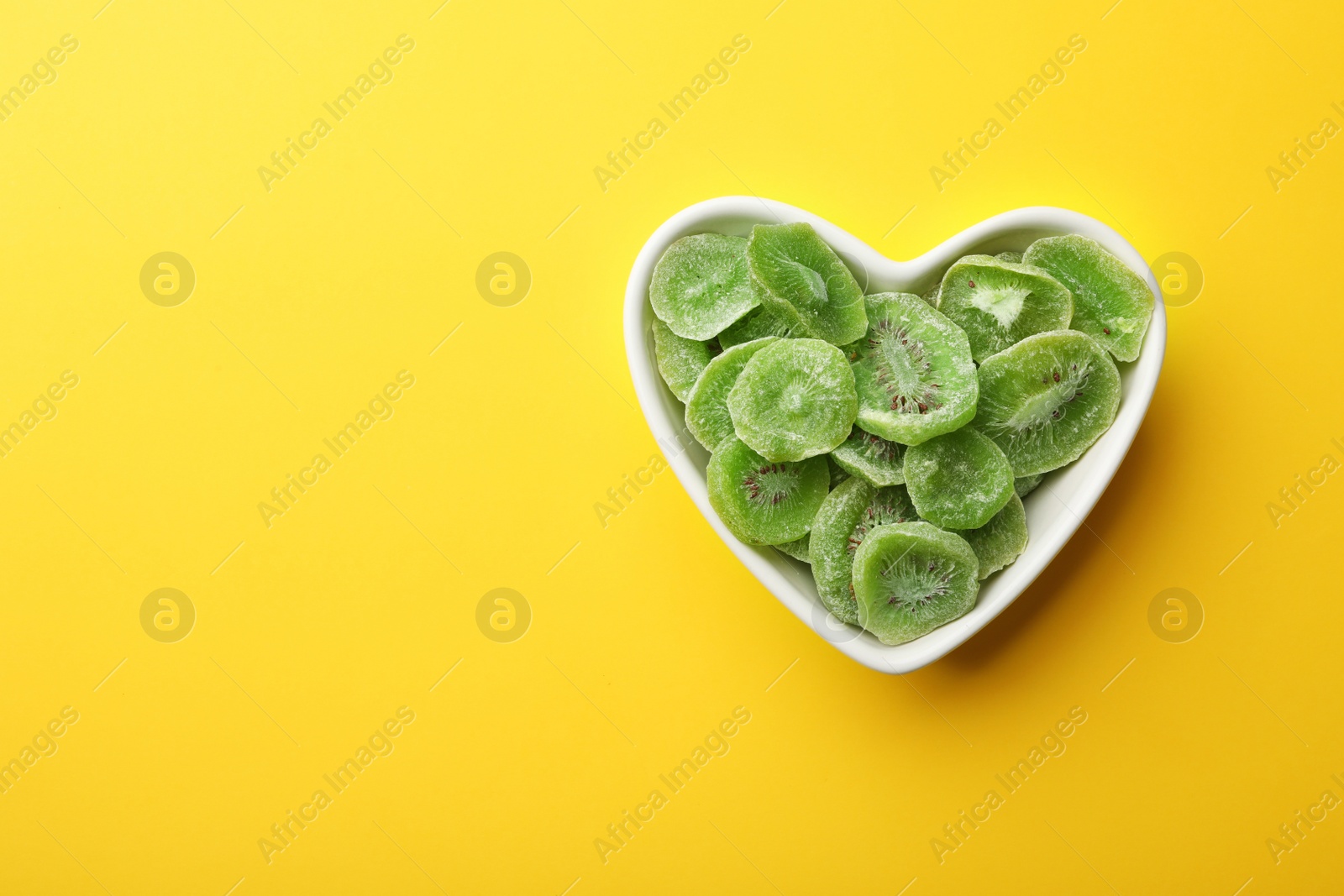 Photo of Bowl of dried kiwi on color background, top view with space for text. Tasty and healthy fruit