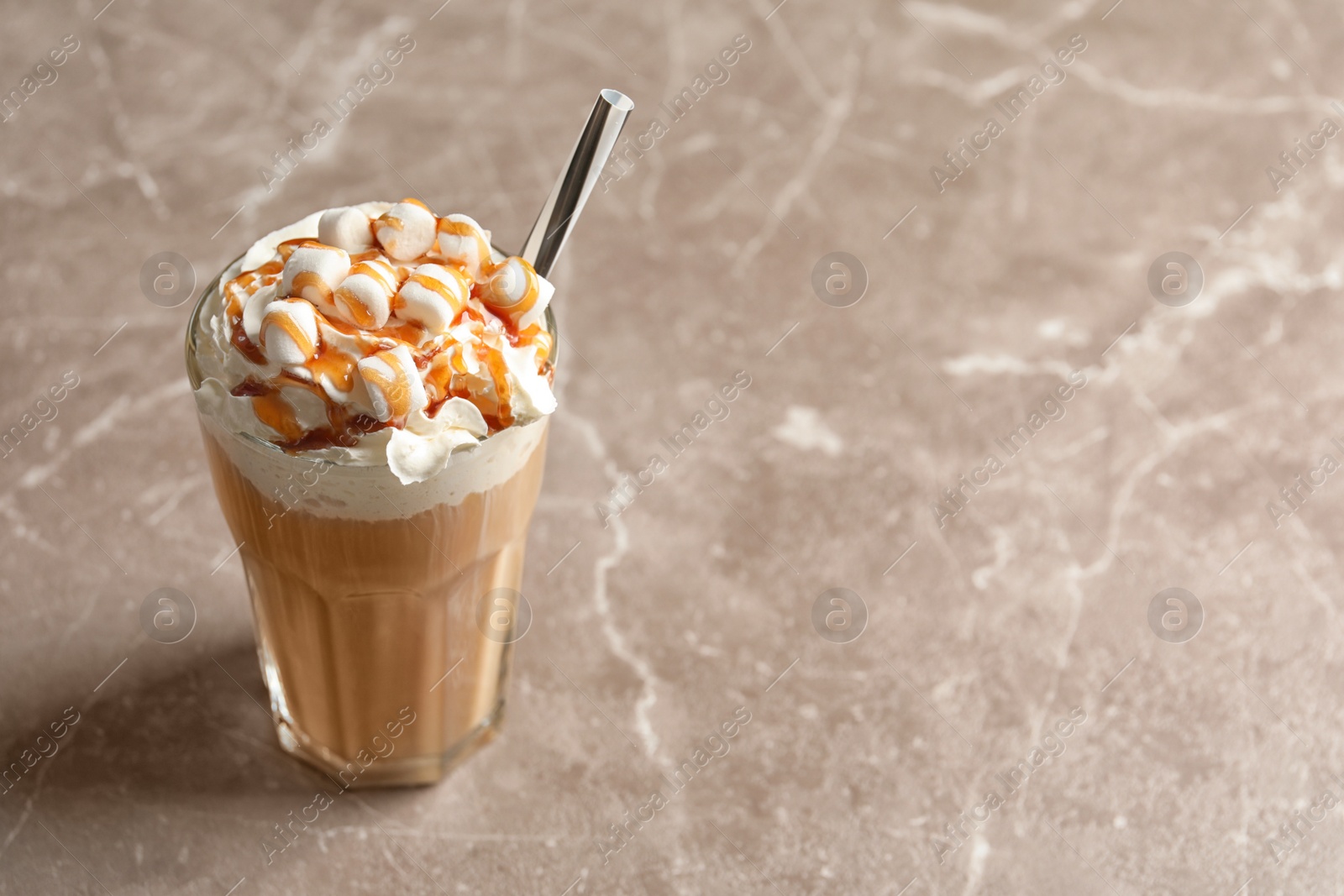 Photo of Glass with delicious caramel frappe on grey background