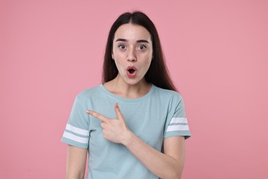 Photo of Portrait of surprised woman pointing at something on pink background