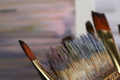 Closeup view of many different paint brushes on blurred background