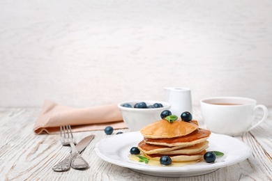 Tasty pancakes with honey and berries on table