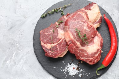 Photo of Fresh raw beef cut with different spices on light grey textured table, top view. Space for text