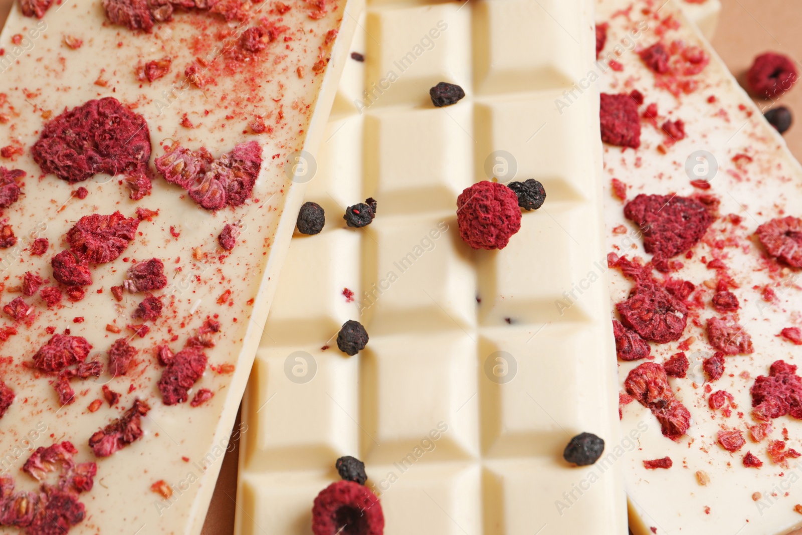 Photo of White chocolate bars with freeze dried fruits as background, closeup