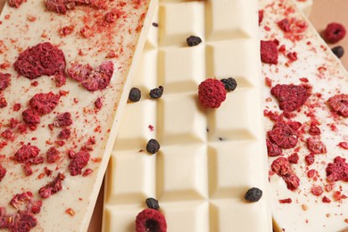 Photo of White chocolate bars with freeze dried fruits as background, closeup