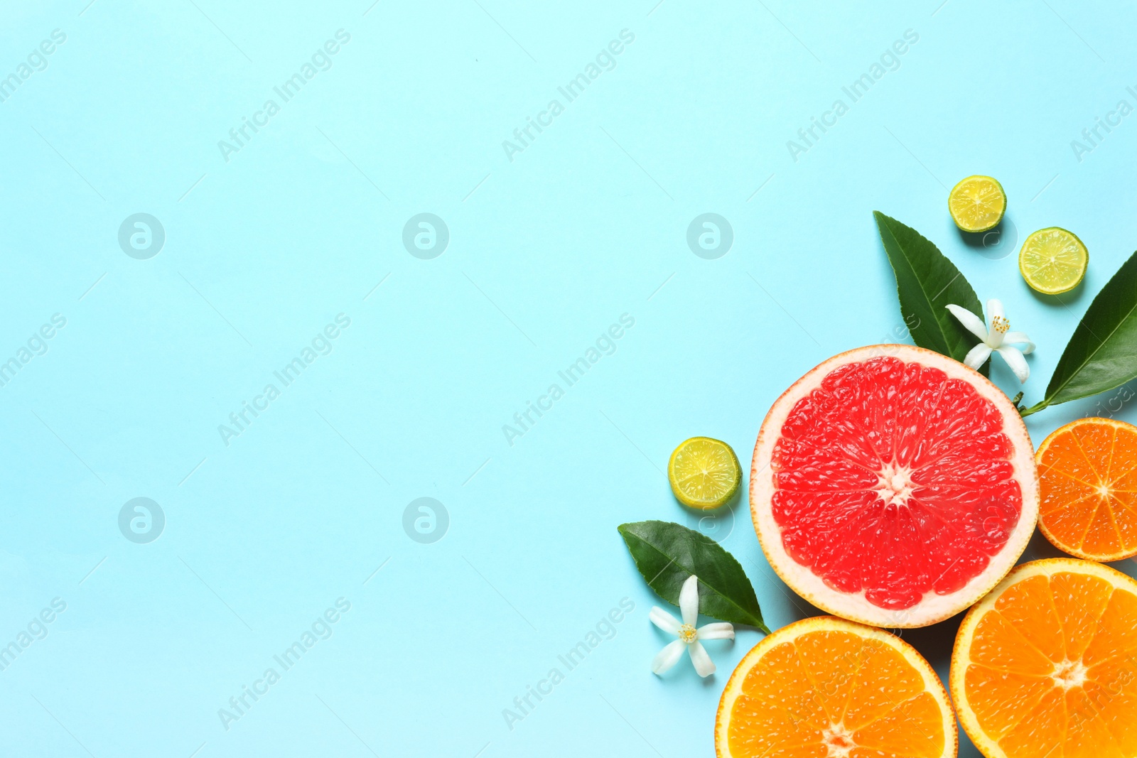 Photo of Flat lay composition with citrus fruits, leaves and flowers on color background. Space for text