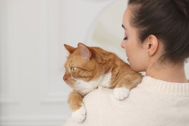 Photo of Woman with cute cat at home, back view. Space for text