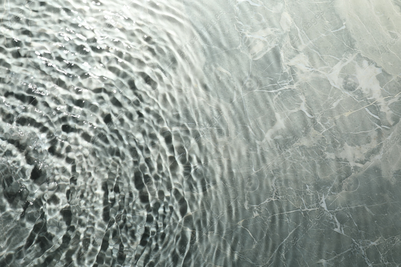 Photo of Rippled surface of clear water on light grey textured background, top view