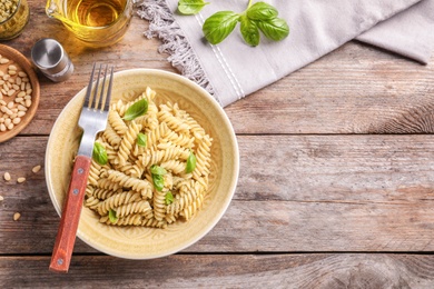 Photo of Plate of delicious basil pesto pasta served for dinner on table, flat lay with space for text