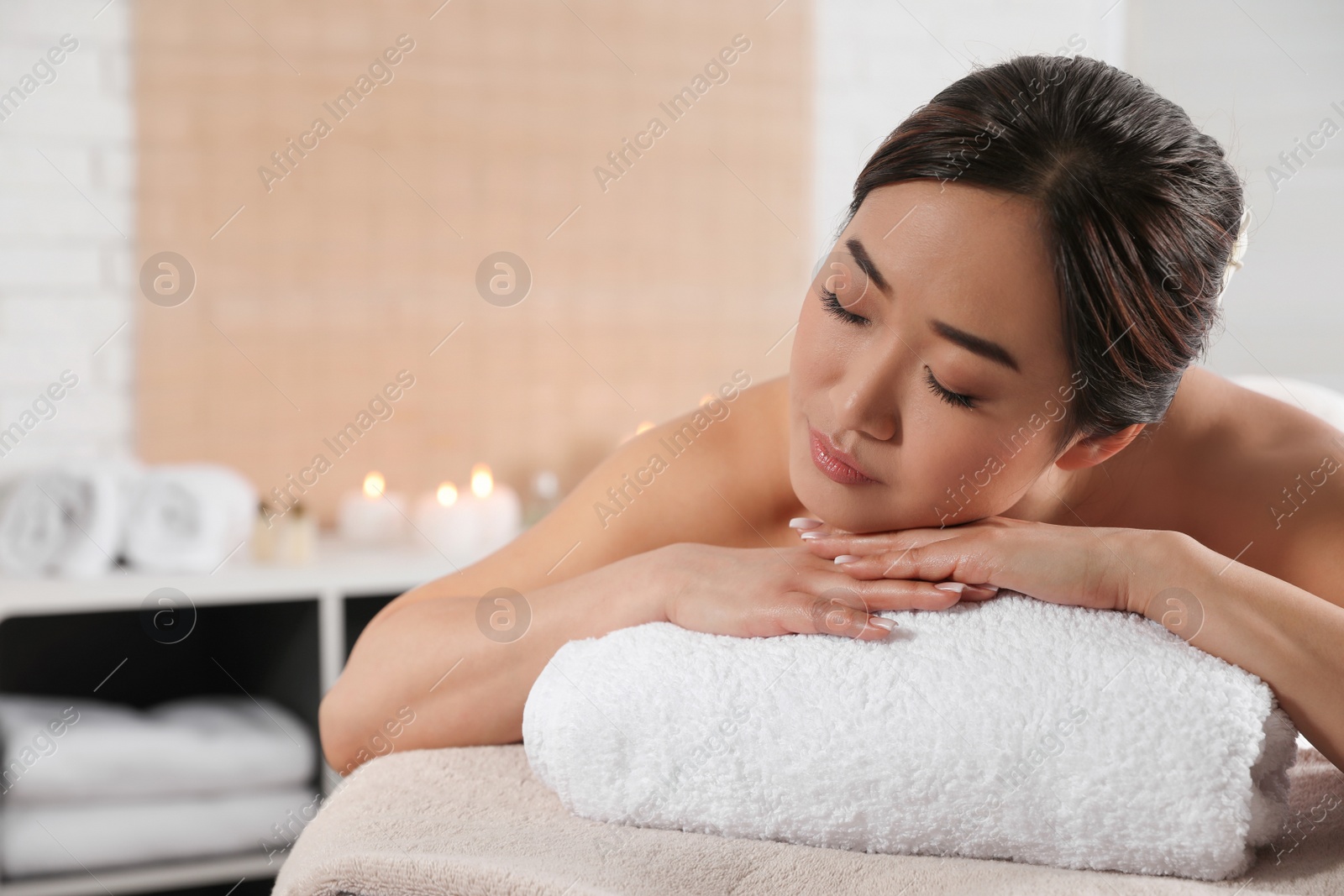 Photo of Beautiful Asian woman lying on massage table in spa salon. Space for text